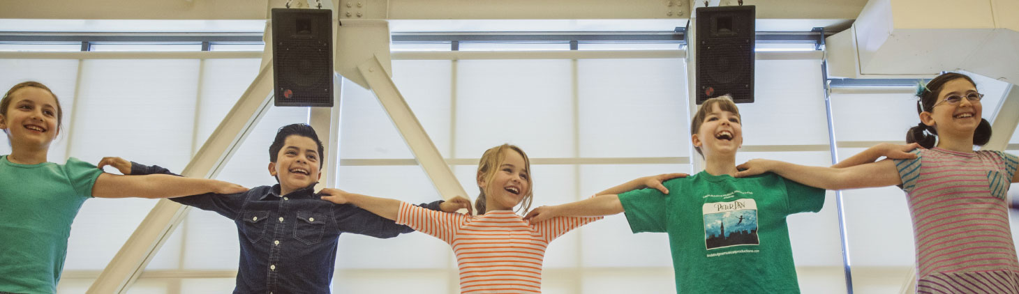 Five young dance students link arms