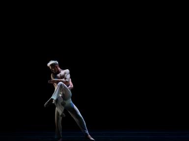 Two ODC Dance Dancers embracing on a dark stage